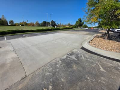 Replaced concrete section in a parking lot drive lane next to a landscaped island